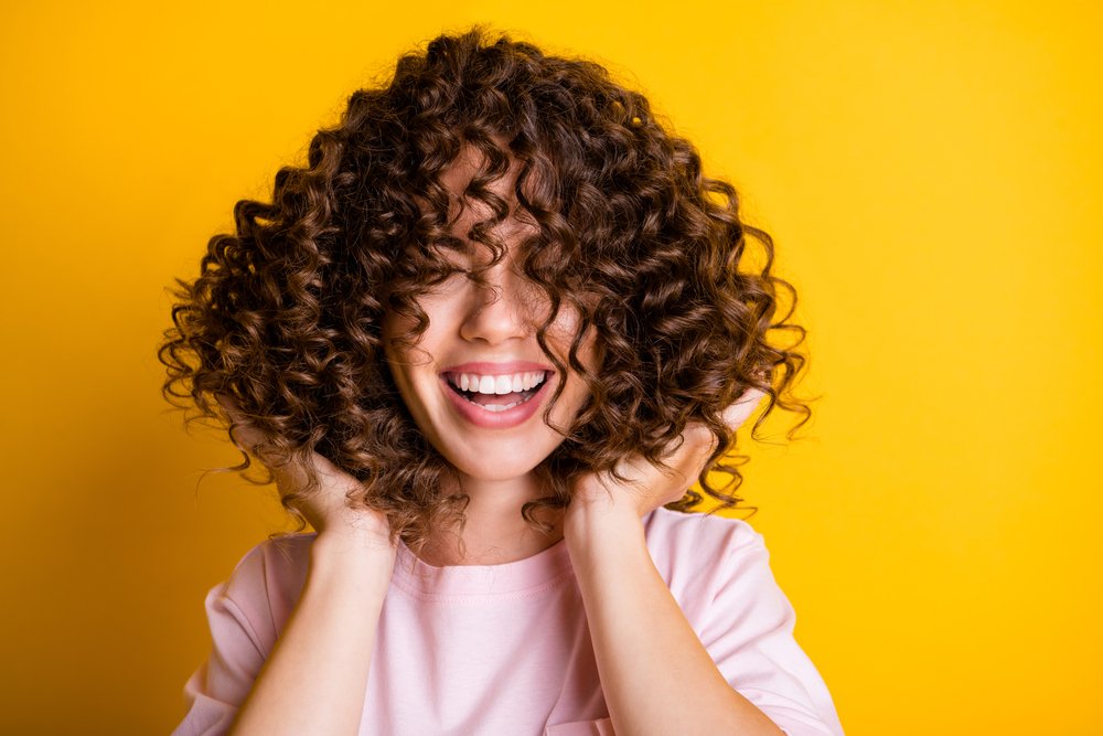 a young woman with curly hair is laughing